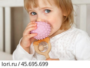 Cute baby girl playing tactile wooden and silicone toys. Young child hand plays sensory massage ball. Enhance the cognitive, physical process. Brain development. Teething toy. Dentition. Baby's teeth. Стоковое фото, фотограф Марина Демидюк / Фотобанк Лори