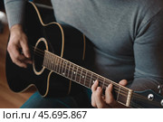 Playing the guitar. Strumming acoustic guitar. Musician plays music. Man fingers holding mediator. Man hand playing guitar neck in dark room. Unrecognizable person rehearsing, fretboard close-up. Стоковое фото, фотограф Марина Демидюк / Фотобанк Лори
