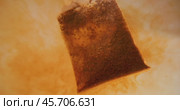 Close up of tea bag diffusing in a clear glass. Macro slow motion shot of the process of brewing herbal. Стоковое видео, видеограф Андрей Армягов / Фотобанк Лори