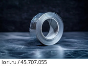 Roll of self adhesive bitumen waterproofing tape lying on a scratched metal surface. Стоковое AI-изображение, AI-художник Иван Рябоконь / Фотобанк Лори