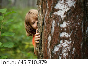 Boy peeking out from behind a tree trunk. Стоковое фото, фотограф Дмитрий Киселёв / Фотобанк Лори