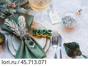Stylish plates, napkin, glass, champagne, Christmas tree branches and Christmas decorations on a gray background. Table setting. The concept of Merry Christmas and New Year 2025. Стоковое фото, фотограф Photojuli / Фотобанк Лори