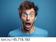 Shocked man opening his mouth and eyes in amazement on blue background. Стоковое AI-изображение, AI-художник Иван Рябоконь / Фотобанк Лори