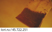 Close up of tea bag diffusing in a clear glass. Macro slow motion shot of the process of brewing herbal. Стоковое видео, видеограф Андрей Армягов / Фотобанк Лори