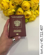 Паспорт Российской федерации в красивой женской руке рядом с букетом цветов. Стоковое фото, фотограф Денис Костров / Фотобанк Лори