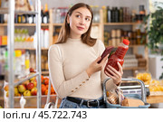 Girl customer holds bottle of tomato juice in hand, scans QR code on product label. Стоковое фото, фотограф Яков Филимонов / Фотобанк Лори