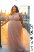 Plus size woman wearing elegant dress enjoying sunset view from rooftop. Стоковое AI-изображение, AI-художник Юрий Поздников / Фотобанк Лори