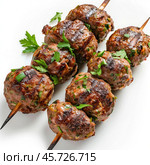 Grilled kofta kebabs with fresh parsley on wooden skewers grilling on white background. Стоковое AI-изображение, AI-художник Иван Рябоконь / Фотобанк Лори