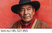 A man wears a traditional hat and colorful clothing, standing confidently in front of a striking orange wall. Native American culture concept. Стоковое AI-видео, аниматор Ксения Лаптева / Фотобанк Лори