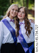 Two happy graduates wearing graduation sashes, celebrating their last school day and the end of their school years. Стоковое фото, фотограф Mikhail Davidovich / Фотобанк Лори