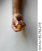 Hand holding yellow die with six dots reflecting chance and game concepts. Стоковое фото, фотограф Lamina Akulova / Фотобанк Лори