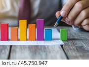 Person Holding a Pen Pointing Colorful Financial Charts, Analysis, Business Activities. Professional is Analyzing a Bar Graph, Data Trends, Report. Businessman Analyzing Document. Growth. Investment. Стоковое AI-изображение, AI-художник Марина Демидюк / Фотобанк Лори