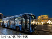 Московский электробус, украшенный праздничными новогодними (рождественскими) электрическими гирляндами, на остановке перед Большим театром в Москве ранним утром. Россия. Стоковое фото, фотограф Наталья Волкова / Фотобанк Лори