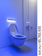Modern white toilet illuminated with blue ambient light in a contemporary bathroom. Стоковое AI-изображение, AI-художник Юрий Поздников / Фотобанк Лори