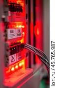 Server room with red lights flashing, showing network cables and electronics. Стоковое AI-изображение, AI-художник Юрий Поздников / Фотобанк Лори