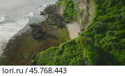 A scenic cliff above the ocean with lush greenery and sandy beach below (2024 год). Редакционное видео, видеограф Степанов Григорий / Фотобанк Лори