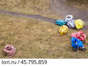 Cleaning the yard with a rake, on the ground are bags of garbage and leaves (2020 год). Редакционное фото, фотограф Коханова Наталья / Фотобанк Лори