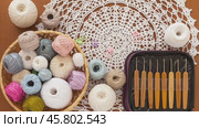Video of handicraft accessories - set of crochet hooks in case, balls of cotton yarn for crocheting in wicker basket and beautiful handmade lace napkin on wooden table. Flat lay, close-up, top view. Стоковое видео, видеограф Виктория Катьянова / Фотобанк Лори