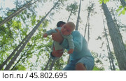 A bearded man pulls an infant in his arms away from the camera, whose face occupied the entire frame. Bottom angle. Sunlit forest in the background. A father and his son on a walk in the nature. Стоковое видео, видеограф Воловодов Владимир / Фотобанк Лори