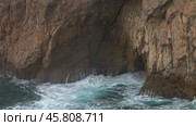 Sea waves enter a cave in rock and form splashes. Стоковое видео, видеограф Михаил Коханчиков / Фотобанк Лори