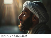 Portrait of a muslim immersed in contemplative prayer against a dark background with rays of light. Shallow depth of field. Стоковое AI-изображение, AI-художник Михаил Строгалев / Фотобанк Лори