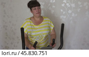 Overweight woman exercising on trainer ellipsoid. Стоковое видео, видеограф Михаил Коханчиков / Фотобанк Лори