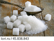 Sugar pile in a metal spoon on a wood surface. White granulated sugar and cubes. Natural seasoning. Refined sugar poured on wooden rustic table. Sugary sand. Cooking, cosmetology, spa services concept. Стоковое AI-изображение, AI-художник Марина Демидюк / Фотобанк Лори