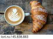Cup of frothy cappuccino coffee with croissants on rustic wood background. Hot coffee latte with art milk foam and freshly-baked Brioche on table in cafe. Breakfast or coffee break. Morning ritual. Стоковое AI-изображение, AI-художник Марина Демидюк / Фотобанк Лори