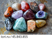 Colorful tumbled gemstones creating a vibrant collection on a textured stone surface. Стоковое AI-изображение, AI-художник Иван Рябоконь / Фотобанк Лори