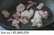 Pieces of bacon are fried in a non-stick frying pan. Стоковое видео, видеограф Георгий Дзюра / Фотобанк Лори