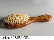 Wooden bath brush with natural bristles is lying on white background. Стоковое AI-изображение, AI-художник Иван Рябоконь / Фотобанк Лори