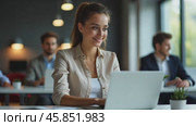 Young Woman Working on Laptop in Modern Office With Colleagues Engaged in Conversation and Teamwork. Стоковое AI-видео, аниматор Sergey Grishin / Фотобанк Лори