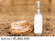 Milk bottle and slices of fresh wheat bread on hay. Стоковое фото, фотограф Татьяна Яцевич / Фотобанк Лори