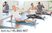 Elderly man performs stretches elastic band with hand and foot while sitting on mat. Стоковое видео, видеограф Яков Филимонов / Фотобанк Лори