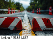 Red and white striped traffic barriers blocking empty road during roadwork. Стоковое AI-изображение, AI-художник Иван Рябоконь / Фотобанк Лори