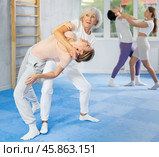 Senior woman applying inverted headlock during mock bout in self-defense training. Стоковое фото, фотограф Яков Филимонов / Фотобанк Лори