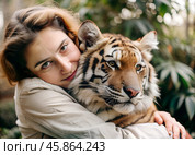 Image portrait of pretty young woman hugging wild tiger. Relationship between man and animals. Wild animals in a natural wildlife habitat. Animal protection, volunteering, nurseries, zoos. Стоковое AI-изображение, AI-художник Анна Сивакова / Фотобанк Лори