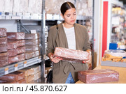 Young woman buys briquettes with red clay in specialized store. Стоковое фото, фотограф Яков Филимонов / Фотобанк Лори