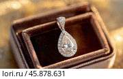 Precious teardrop diamond pendant resting in jewelry box. Стоковое AI-изображение, AI-художник Юрий Поздников / Фотобанк Лори