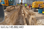 Construction workers installing underground pipes with excavators at building site. Стоковое AI-изображение, AI-художник Юрий Поздников / Фотобанк Лори