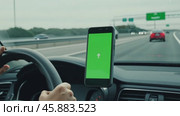 Navigator with green screen in the car dashboard. GPS module. Driver using smart phone with green background. Man steering wheel, driving on highway with smartphone navigation. Digital display monitor. Стоковое AI-видео, аниматор Марина Демидюк / Фотобанк Лори