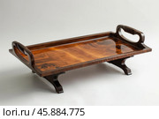 Varnished wooden serving tray with handles and feet standing on white background. Стоковое AI-изображение, AI-художник Иван Рябоконь / Фотобанк Лори
