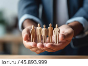 Businessman protecting wooden figures of people with hands. Стоковое AI-изображение, AI-художник Иван Рябоконь / Фотобанк Лори