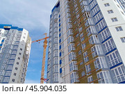 Строящееся высотное здание и подъемный кран на фоне голубого неба. Building crane and building under construction against blue sky. Стоковое фото, фотограф Татьяна Д / Фотобанк Лори