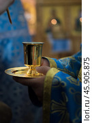 Priest in blue church vestment anoints with sacred oil from gold vessel. Стоковое фото, фотограф irisff / Фотобанк Лори