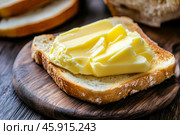 Slice of wholemeal bread with butter curl. Buttering toast. Yellow butter scattered on a piece of bread. Bread with toasting and spreading butter. Generous spread of butter on a rustic bread slice. Стоковое AI-изображение, AI-художник Марина Демидюк / Фотобанк Лори