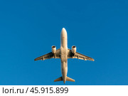 Белый самолет пролетает на фоне голубого неба. Вид снизу. Редакционное фото, фотограф Anton Leonchikov / Фотобанк Лори