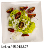 Pile of guacamole on plate, sprinkled with chopped hot onions, decorated with slices of tomatoes. Стоковое фото, фотограф Яков Филимонов / Фотобанк Лори