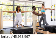 Female pilates trainer helping pilates people during training. Стоковое фото, фотограф Яков Филимонов / Фотобанк Лори