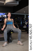 Sportive young woman doing exercises on arm curl device in well-equipped gym. Стоковое видео, видеограф Яков Филимонов / Фотобанк Лори